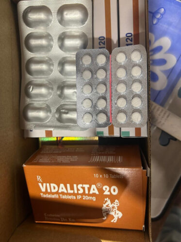 Orange Vidalista 20 box with 'Tadalafil Tablets IP 20mg' beside two blister packs of white round tablets in a cardboard box—medicine packaging visible.
