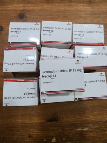 Row of white medicine boxes labeled Ivermectin Tablets IP 12 mg Ivocap-12 on a wooden surface (pharmaceutical packaging)
