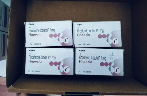 Four white boxes labeled Finpecia Finasteride Tablets IP 1 mg arranged in a cardboard box, 10 x 15 tablets each.