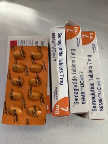 Orange blister pack with round tablets beside white boxes labeled Semaglutide Tablet 7 mg (Torrent Pharma) on a light countertop.