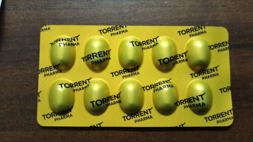 Yellow oval tablets in a Torrent Pharma blister pack on a wood surface.